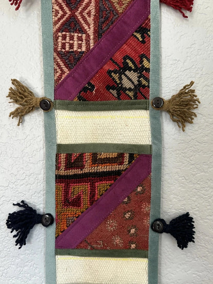 multi-colored three pocket wall organizer made from scraps of colorful Turkish kilim rugs with yarn tassels at each end