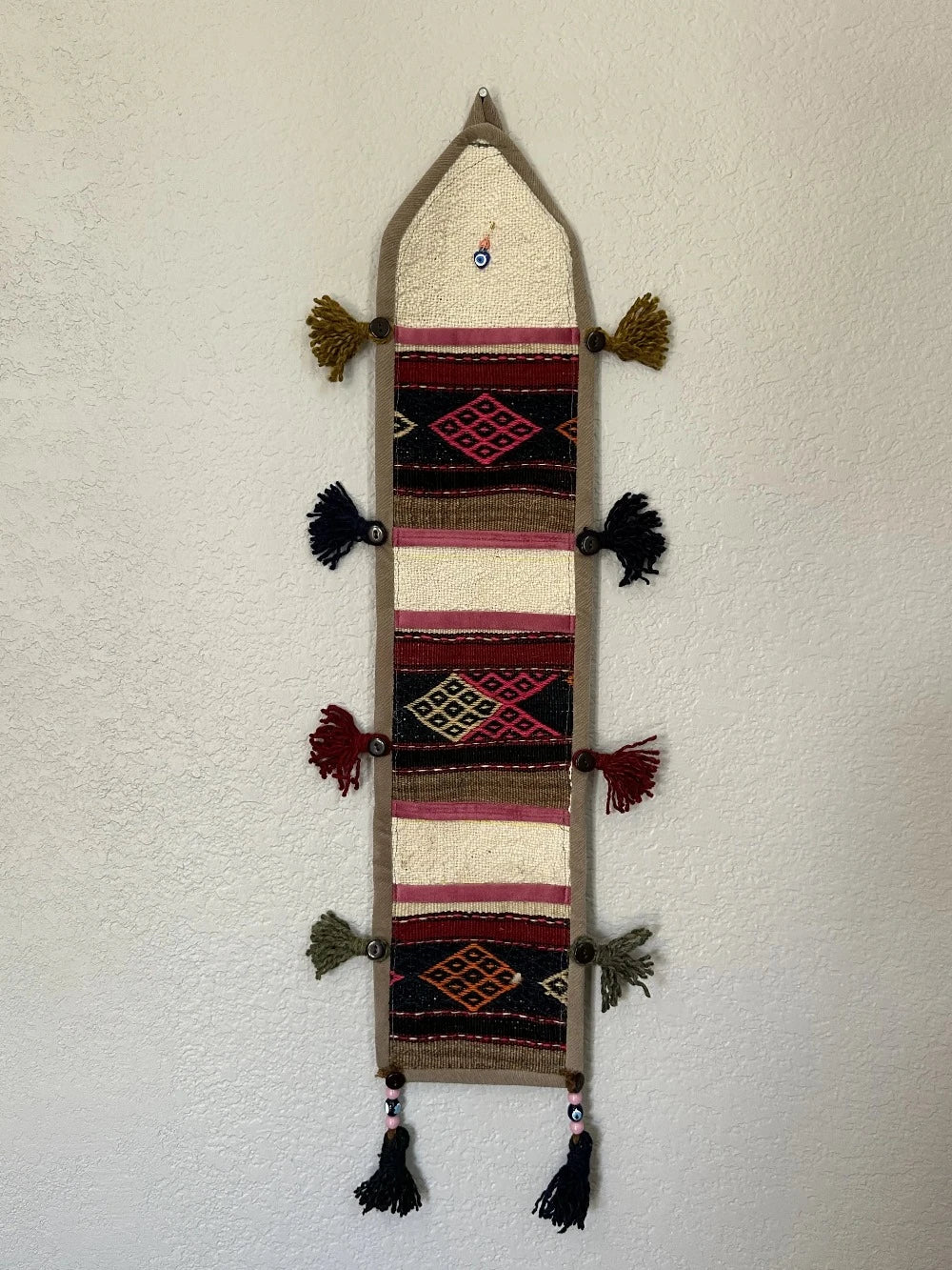 multi-colored three pocket wall organizer made from scraps of colorful Turkish kilim rugs with yarn tassels at each end