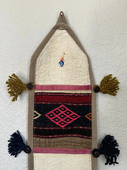 multi-colored three pocket wall organizer made from scraps of colorful Turkish kilim rugs with yarn tassels at each end