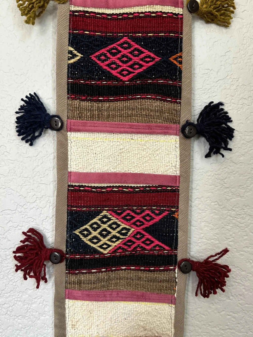 multi-colored three pocket wall organizer made from scraps of colorful Turkish kilim rugs with yarn tassels at each end