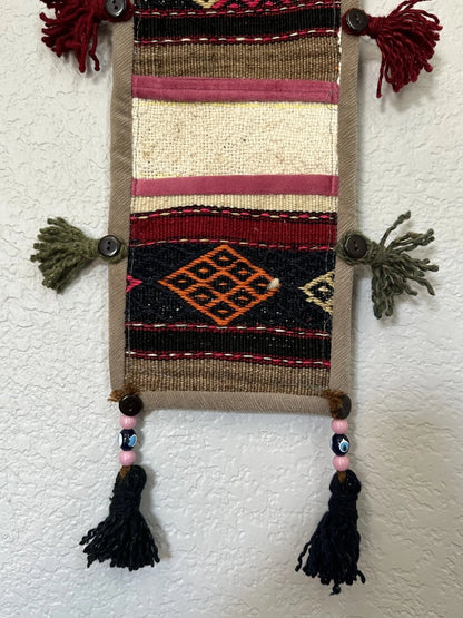 multi-colored three pocket wall organizer made from scraps of colorful Turkish kilim rugs with yarn tassels at each end