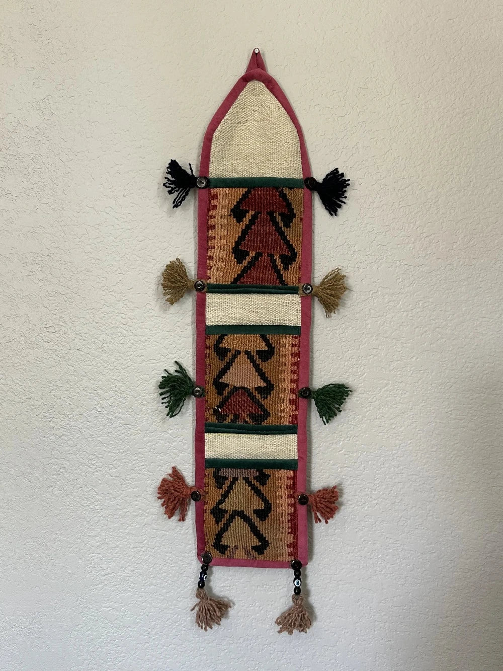 multi-colored three pocket wall organizer made from scraps of colorful Turkish kilim rugs with yarn tassels at each end