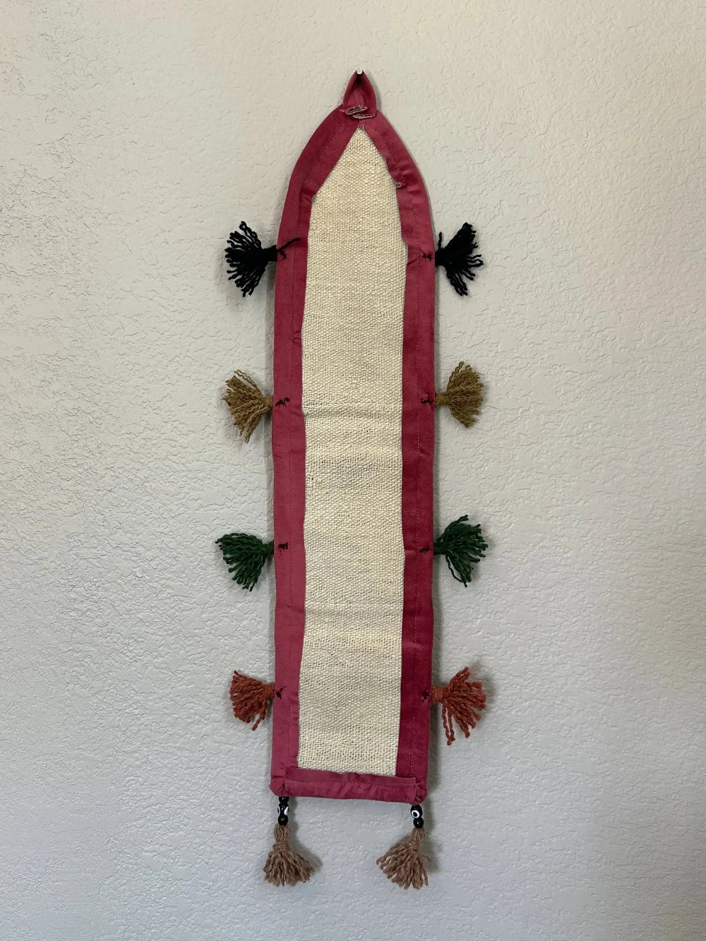 multi-colored three pocket wall organizer made from scraps of colorful Turkish kilim rugs with yarn tassels at each end