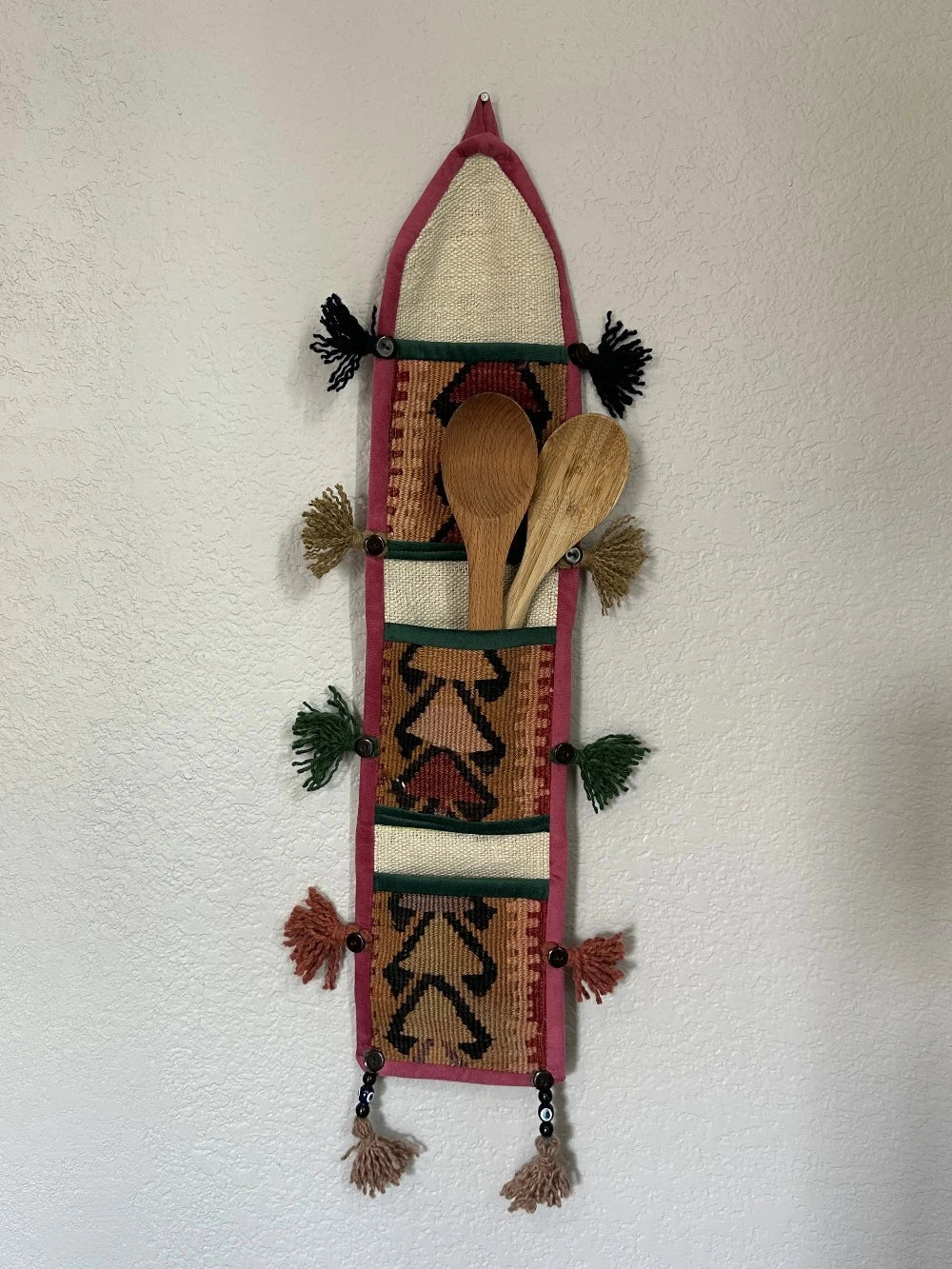 multi-colored three pocket wall organizer made from scraps of colorful Turkish kilim rugs with yarn tassels at each end