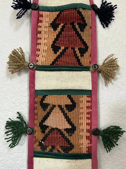 multi-colored three pocket wall organizer made from scraps of colorful Turkish kilim rugs with yarn tassels at each end