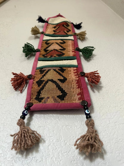 multi-colored three pocket wall organizer made from scraps of colorful Turkish kilim rugs with yarn tassels at each end