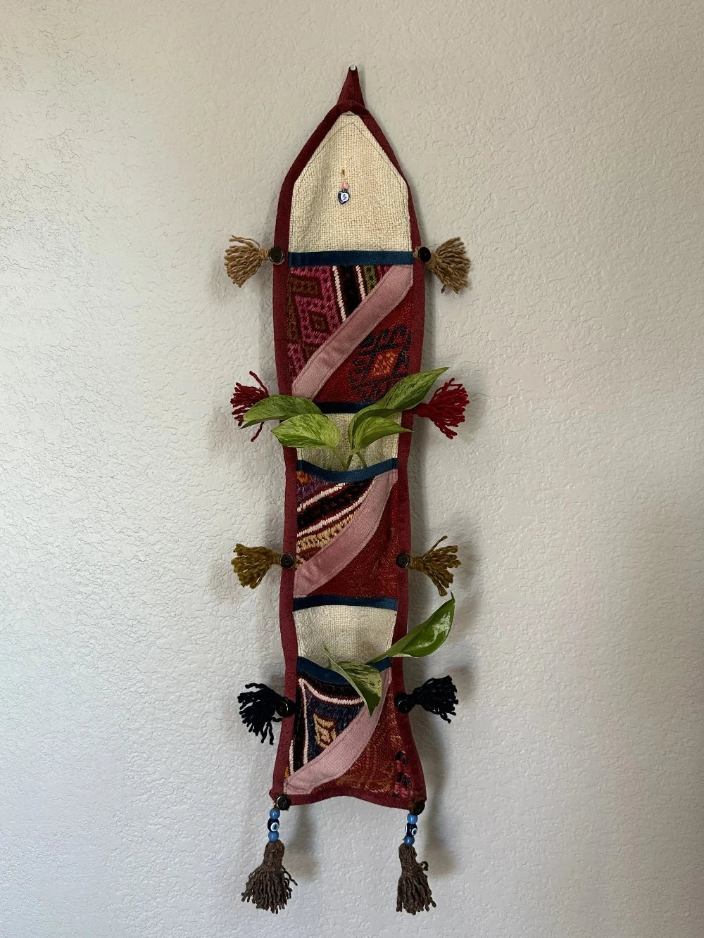 multi-colored three pocket wall organizer made from scraps of colorful Turkish kilim rugs with yarn tassels at each end