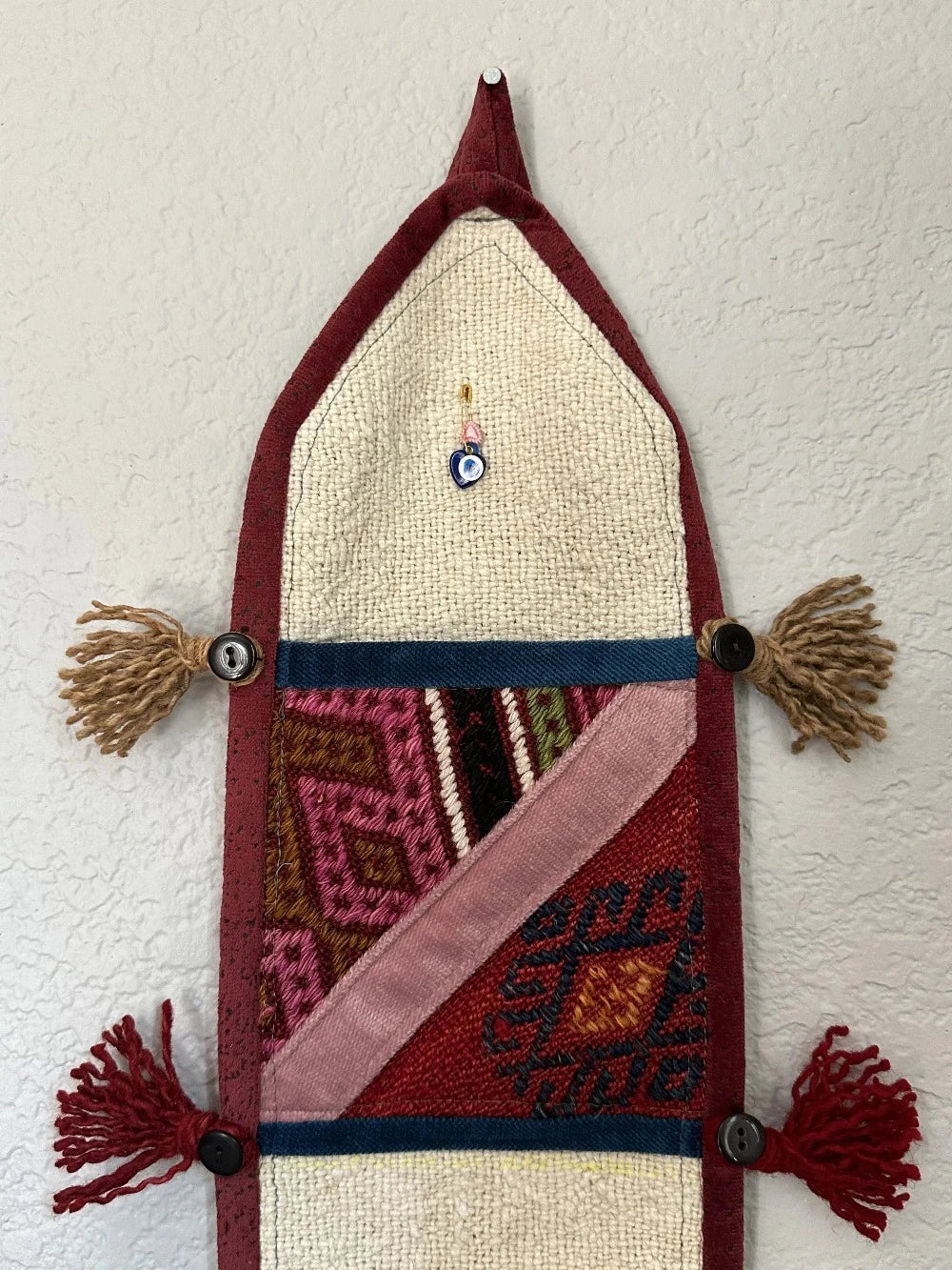 multi-colored three pocket wall organizer made from scraps of colorful Turkish kilim rugs with yarn tassels at each end