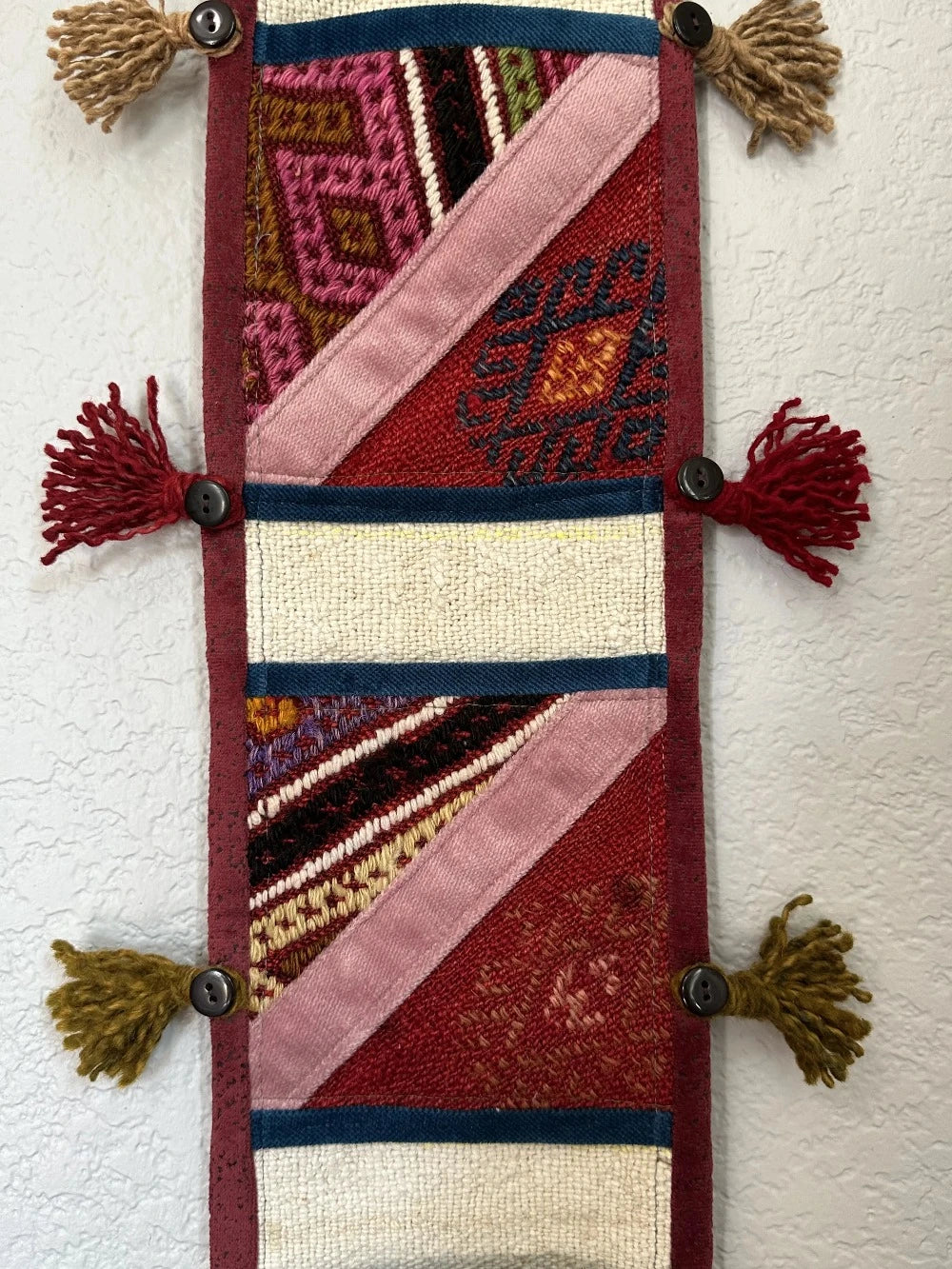 multi-colored three pocket wall organizer made from scraps of colorful Turkish kilim rugs with yarn tassels at each end