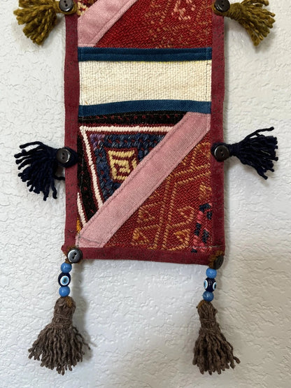 multi-colored three pocket wall organizer made from scraps of colorful Turkish kilim rugs with yarn tassels at each end