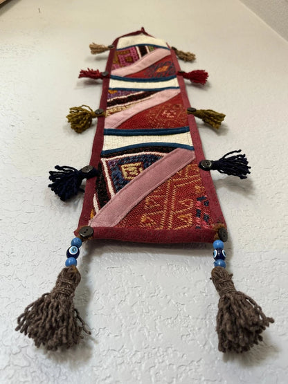 multi-colored three pocket wall organizer made from scraps of colorful Turkish kilim rugs with yarn tassels at each end