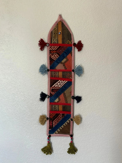 multi-colored three pocket wall organizer made from scraps of colorful Turkish kilim rugs with yarn tassels at each end