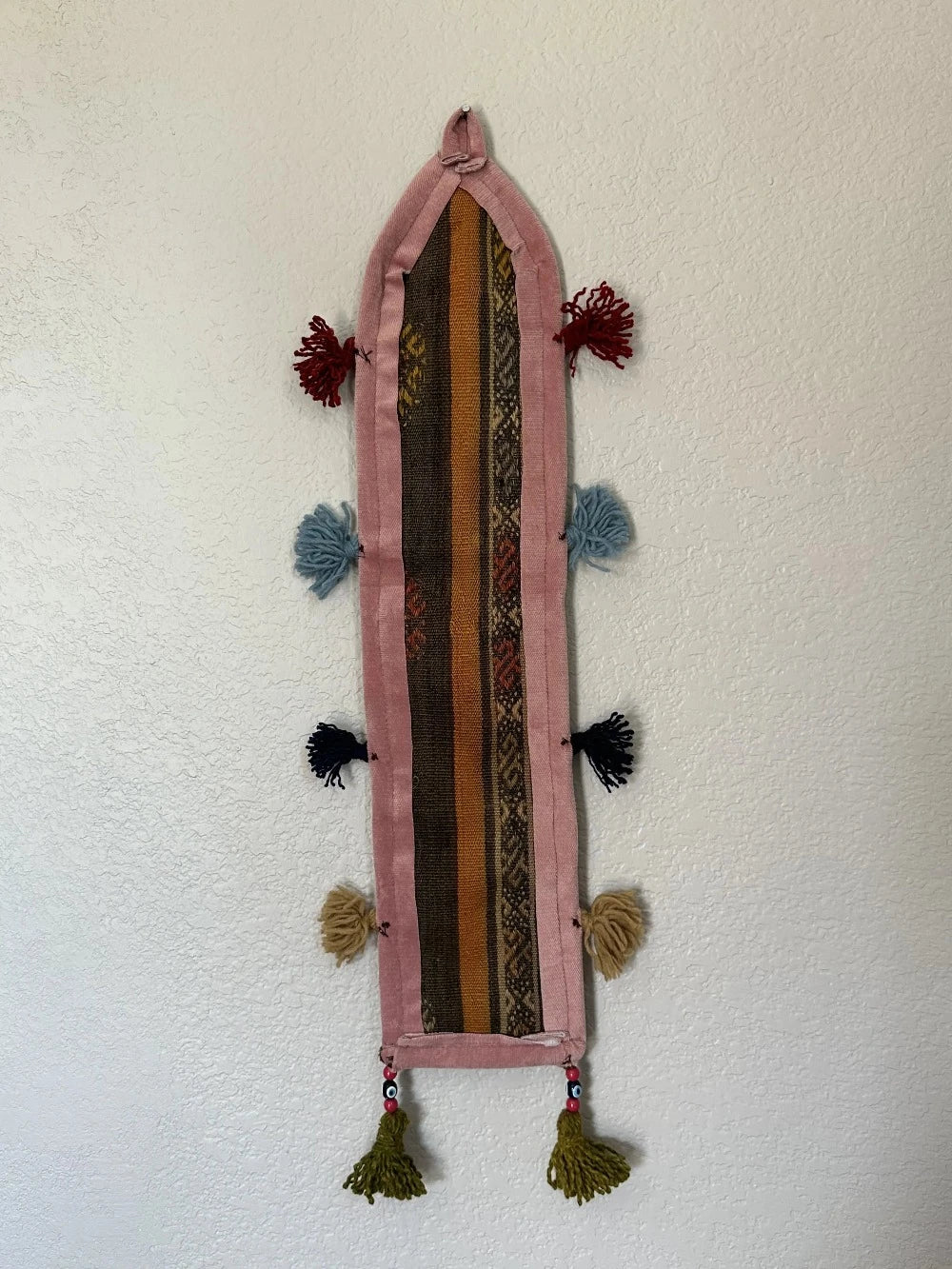 multi-colored three pocket wall organizer made from scraps of colorful Turkish kilim rugs with yarn tassels at each end