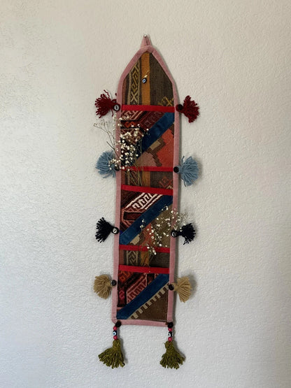 multi-colored three pocket wall organizer made from scraps of colorful Turkish kilim rugs with yarn tassels at each end