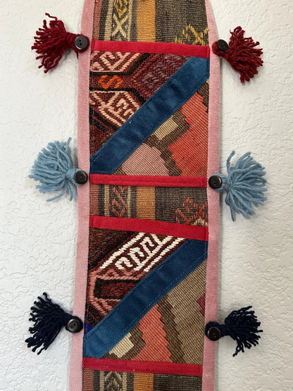 multi-colored three pocket wall organizer made from scraps of colorful Turkish kilim rugs with yarn tassels at each end