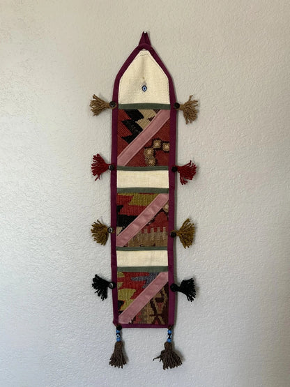 multi-colored three pocket wall organizer made from scraps of colorful Turkish kilim rugs with yarn tassels at each end