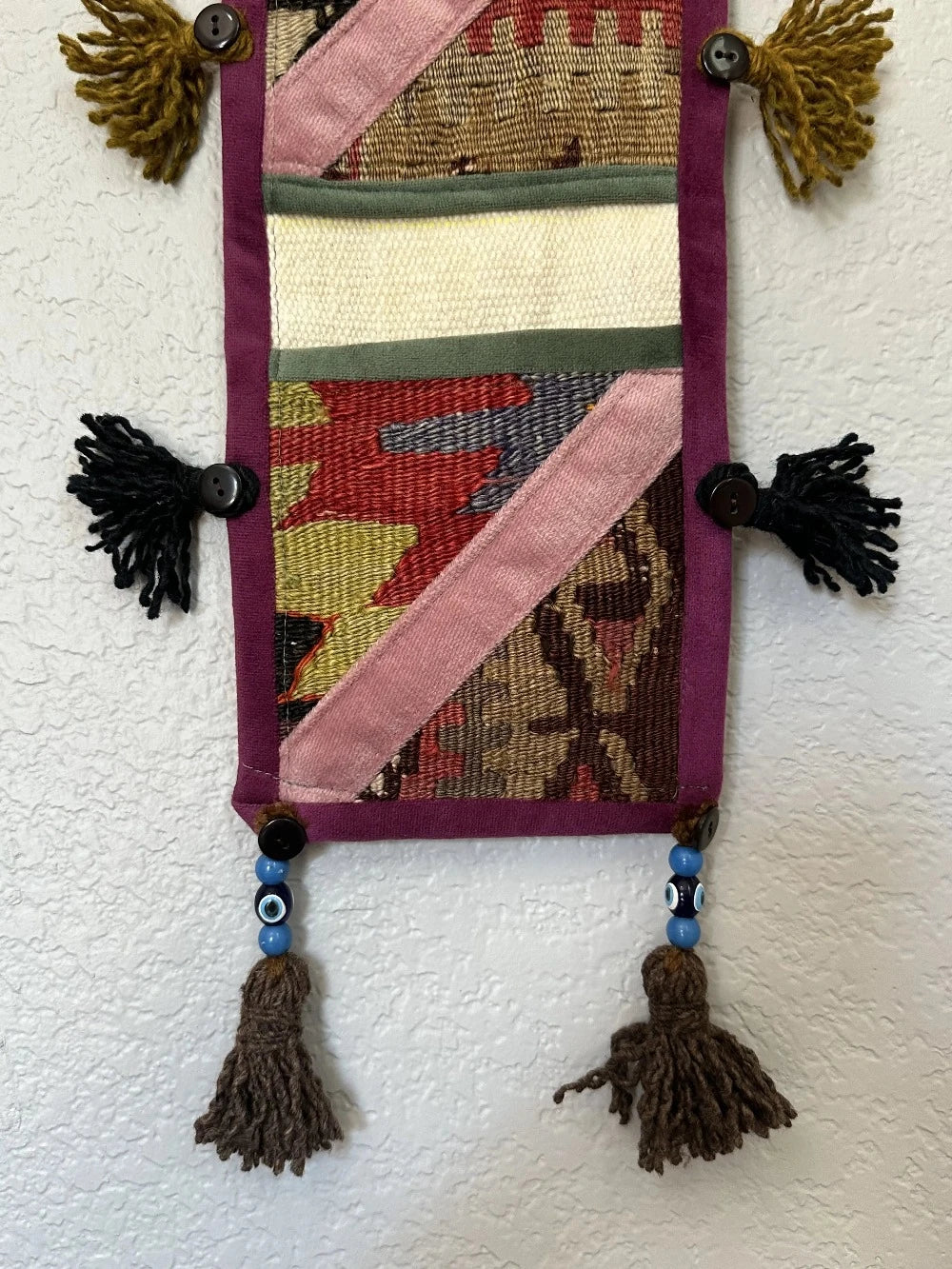 multi-colored three pocket wall organizer made from scraps of colorful Turkish kilim rugs with yarn tassels at each end