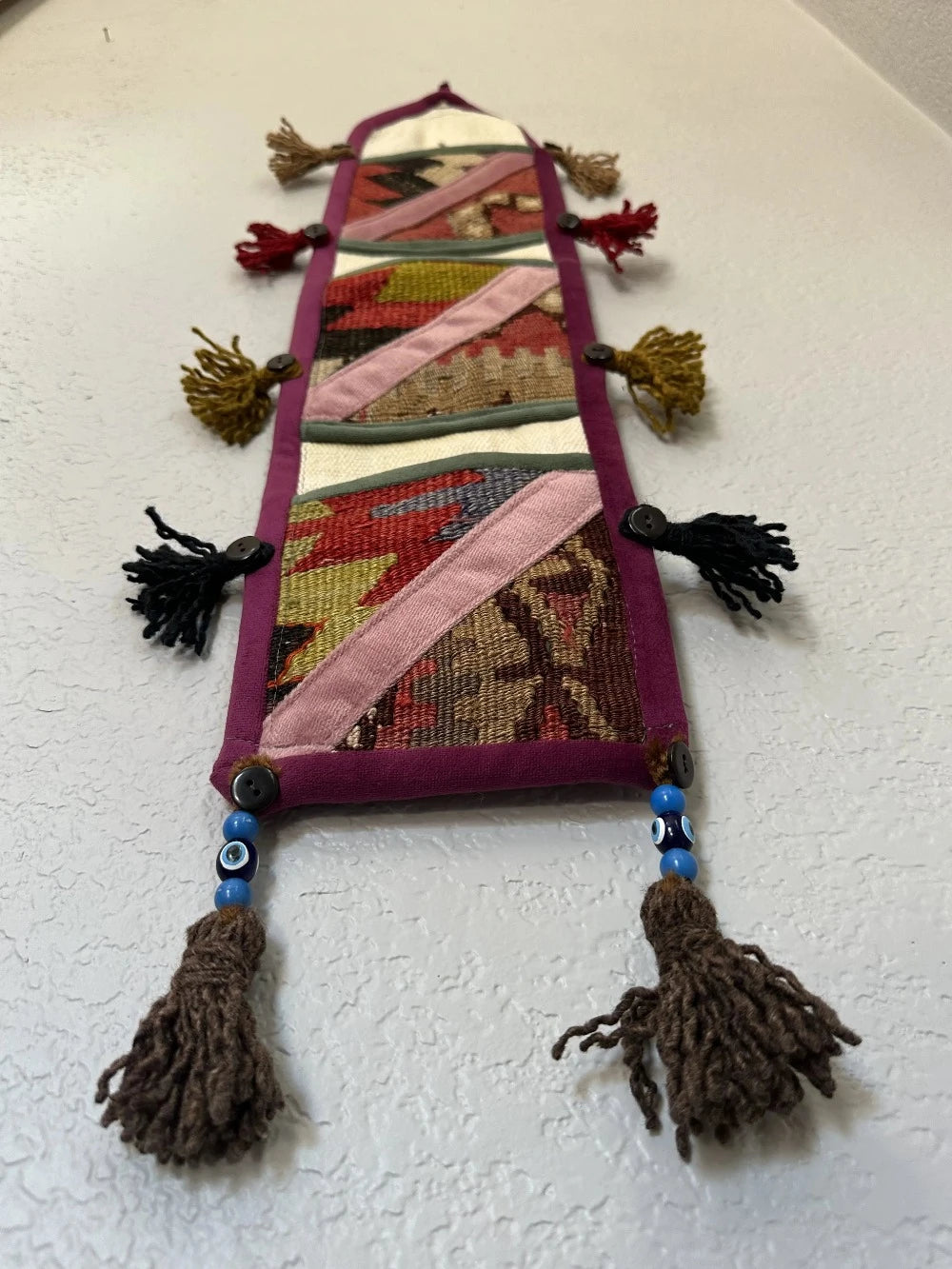 multi-colored three pocket wall organizer made from scraps of colorful Turkish kilim rugs with yarn tassels at each end