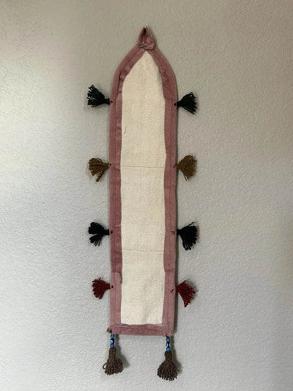 multi-colored three pocket wall organizer made from scraps of colorful Turkish kilim rugs with yarn tassels at each end