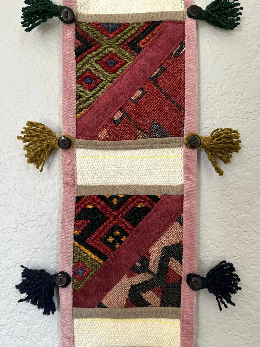 multi-colored three pocket wall organizer made from scraps of colorful Turkish kilim rugs with yarn tassels at each end