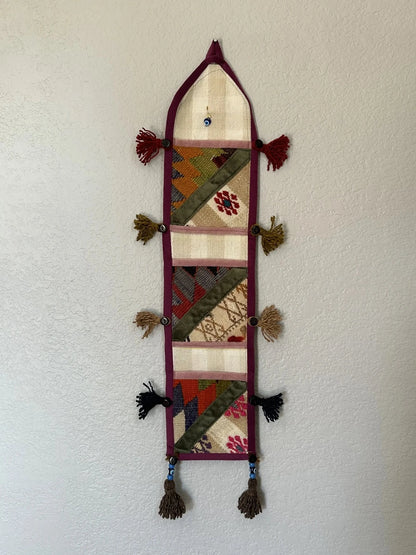 multi-colored three pocket wall organizer made from scraps of colorful Turkish kilim rugs with yarn tassels at each end