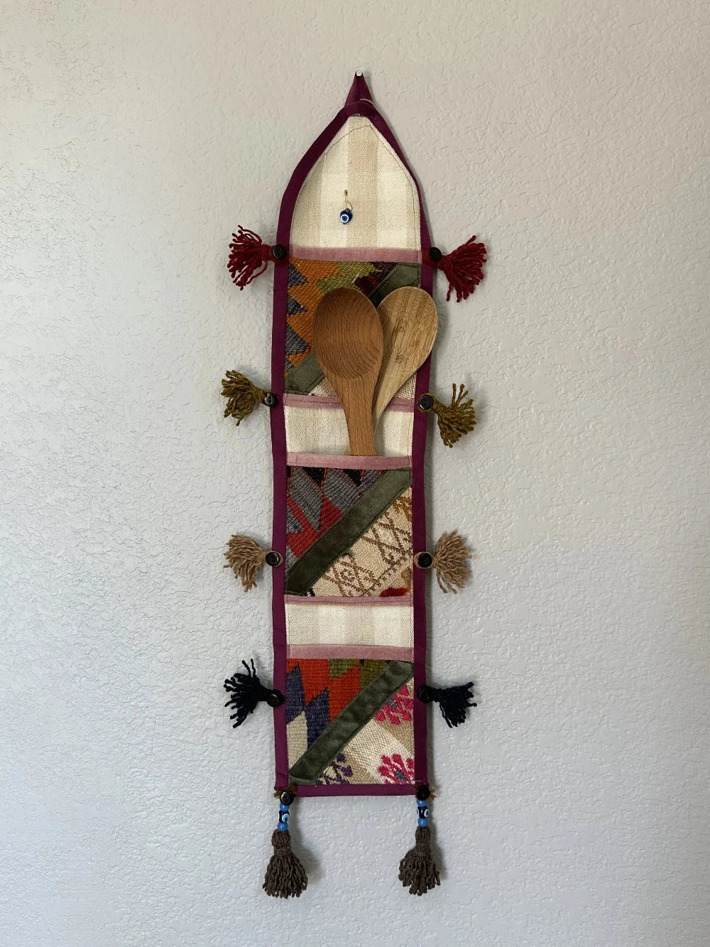 multi-colored three pocket wall organizer made from scraps of colorful Turkish kilim rugs with yarn tassels at each end