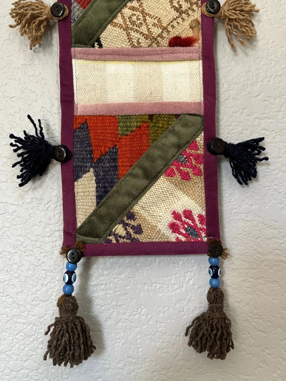 multi-colored three pocket wall organizer made from scraps of colorful Turkish kilim rugs with yarn tassels at each end