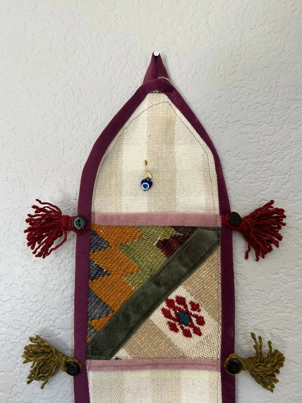 multi-colored three pocket wall organizer made from scraps of colorful Turkish kilim rugs with yarn tassels at each end