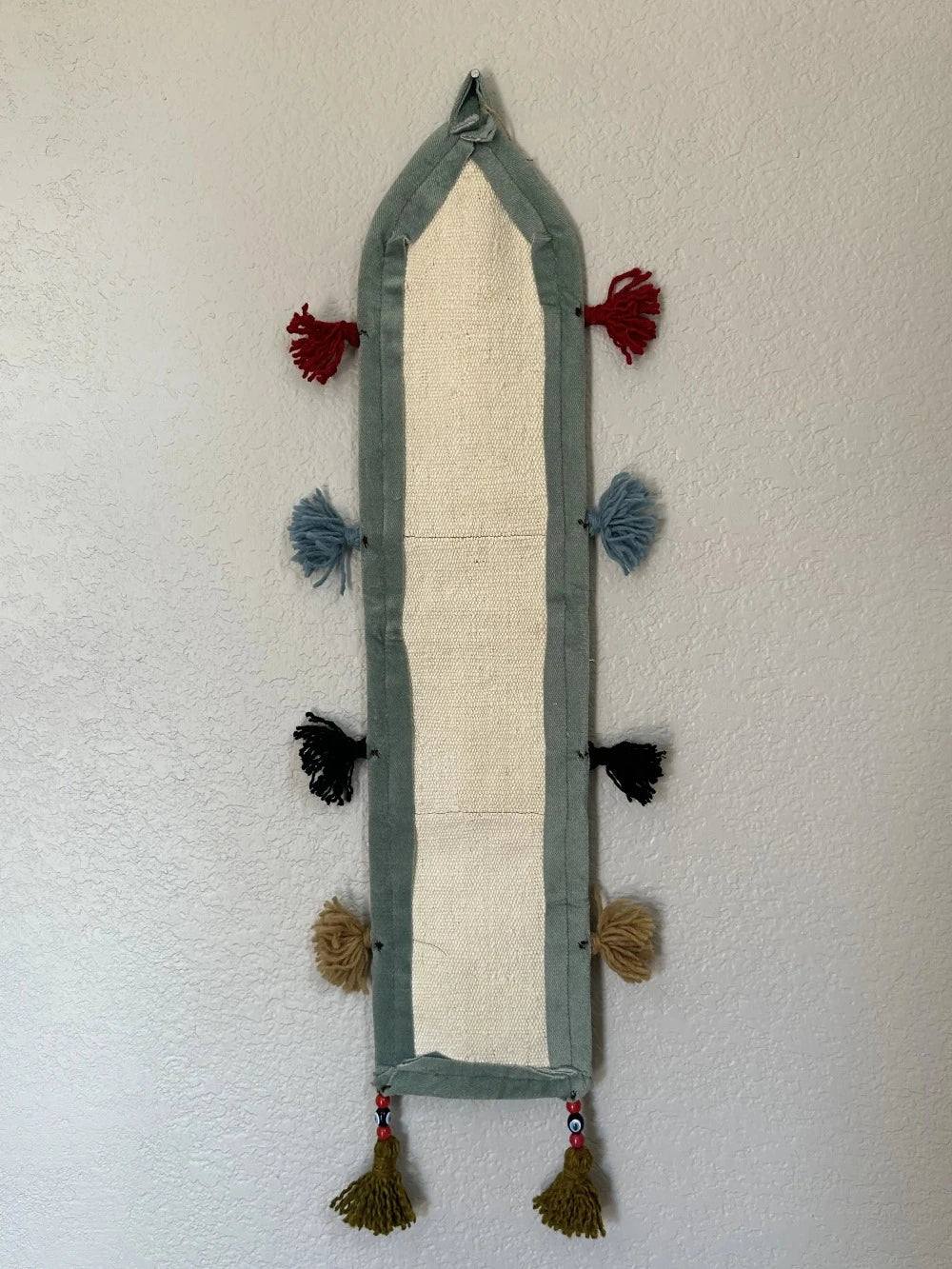 multi-colored three pocket wall organizer made from scraps of colorful Turkish kilim rugs with yarn tassels at each end