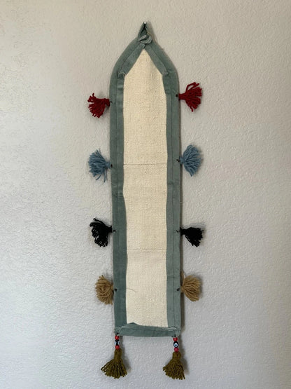 multi-colored three pocket wall organizer made from scraps of colorful Turkish kilim rugs with yarn tassels at each end