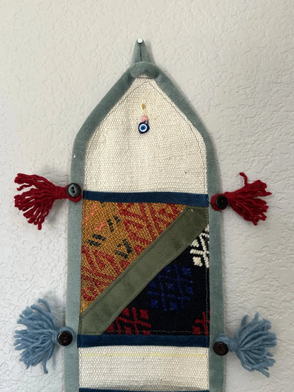 multi-colored three pocket wall organizer made from scraps of colorful Turkish kilim rugs with yarn tassels at each end