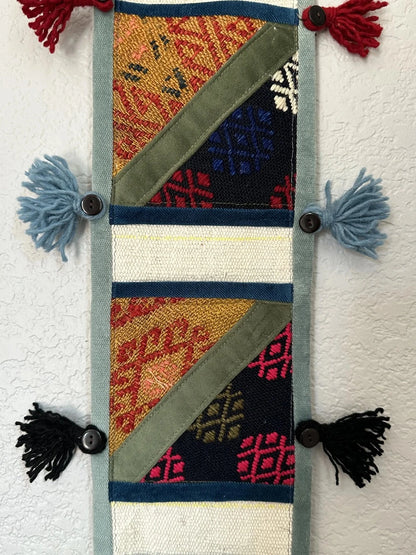 multi-colored three pocket wall organizer made from scraps of colorful Turkish kilim rugs with yarn tassels at each end