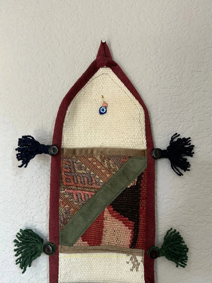 multi-colored three pocket wall organizer made from scraps of colorful Turkish kilim rugs with yarn tassels at each end