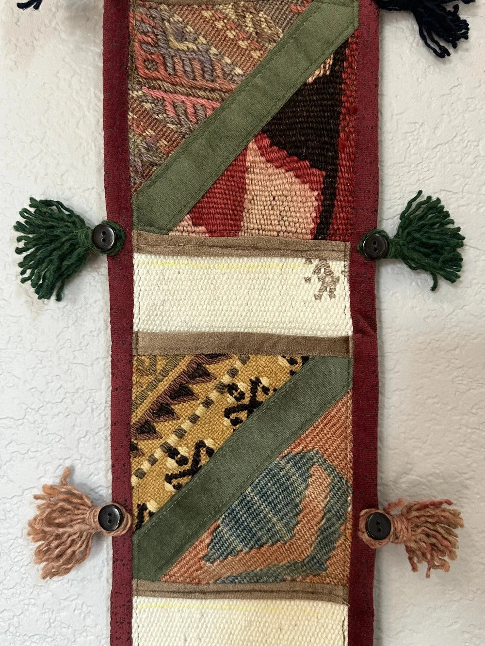 multi-colored three pocket wall organizer made from scraps of colorful Turkish kilim rugs with yarn tassels at each end