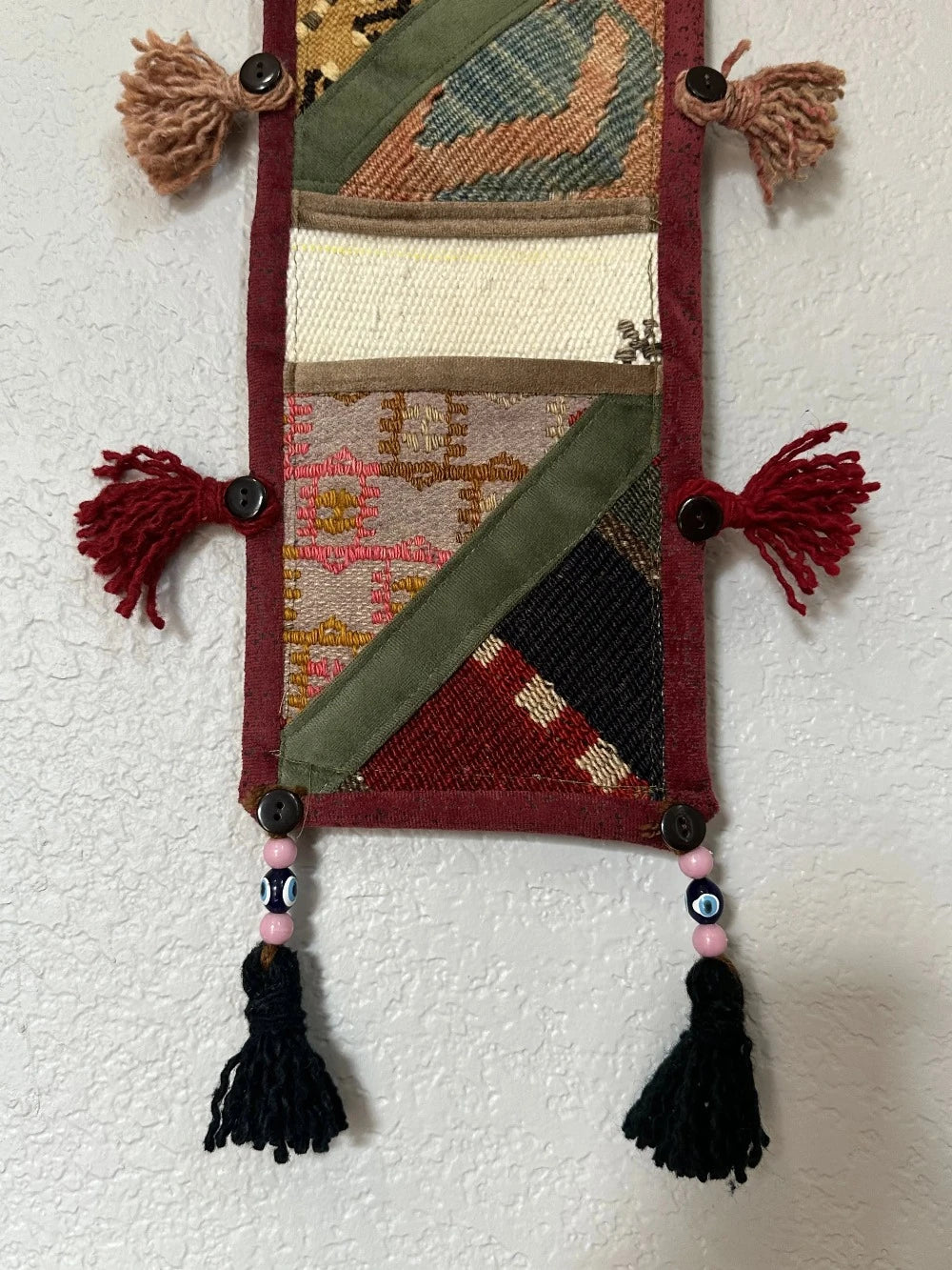 multi-colored three pocket wall organizer made from scraps of colorful Turkish kilim rugs with yarn tassels at each end