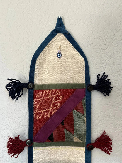 multi-colored three pocket wall organizer made from scraps of colorful Turkish kilim rugs with yarn tassels at each end