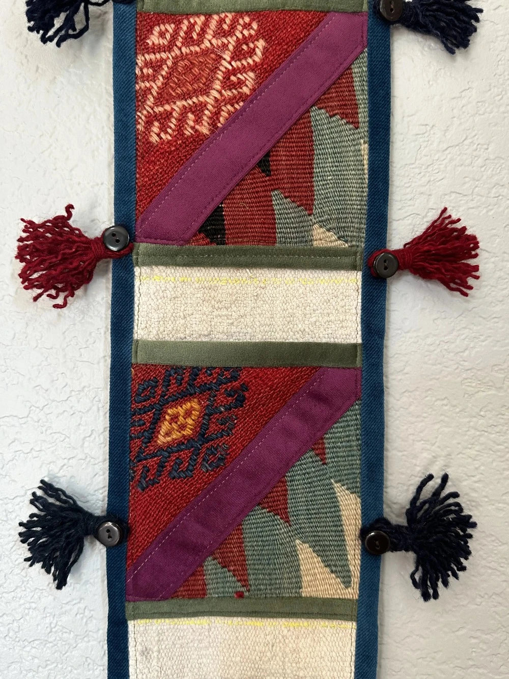 multi-colored three pocket wall organizer made from scraps of colorful Turkish kilim rugs with yarn tassels at each end