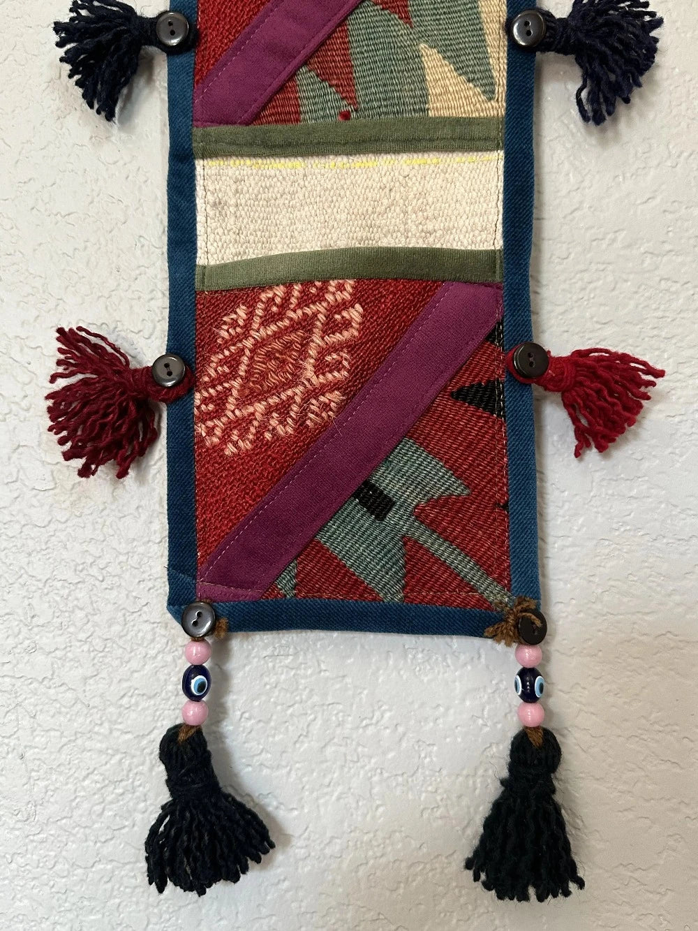 multi-colored three pocket wall organizer made from scraps of colorful Turkish kilim rugs with yarn tassels at each end