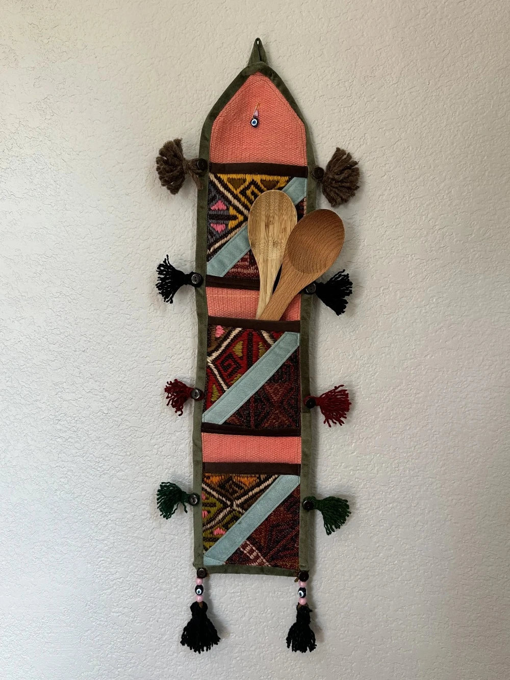 multi-colored three pocket wall organizer made from scraps of colorful Turkish kilim rugs with yarn tassels at each end