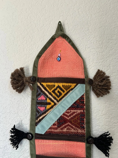 multi-colored three pocket wall organizer made from scraps of colorful Turkish kilim rugs with yarn tassels at each end