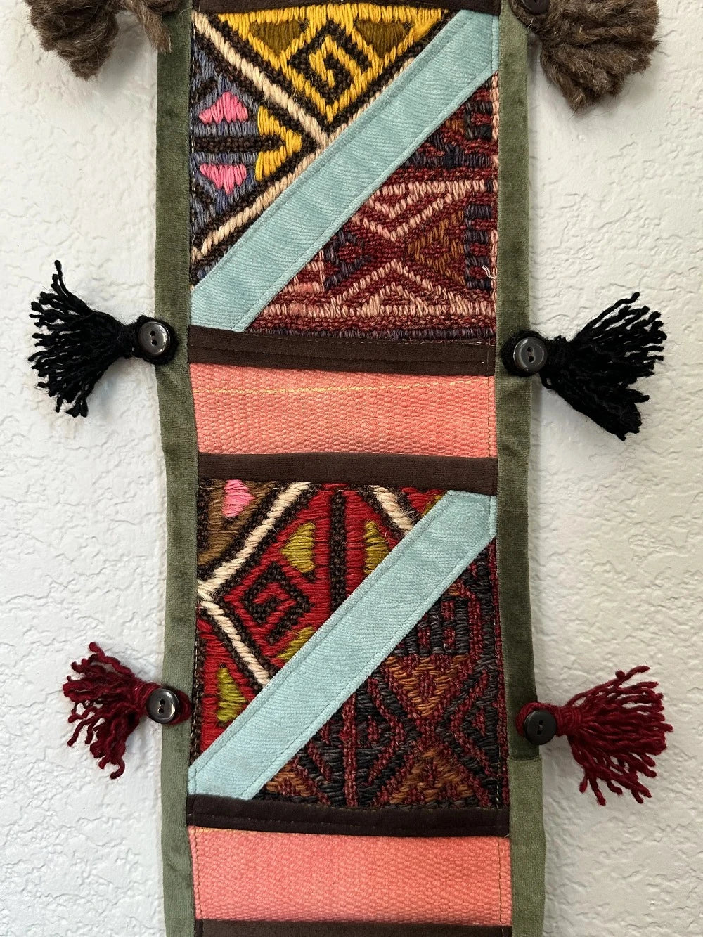 multi-colored three pocket wall organizer made from scraps of colorful Turkish kilim rugs with yarn tassels at each end