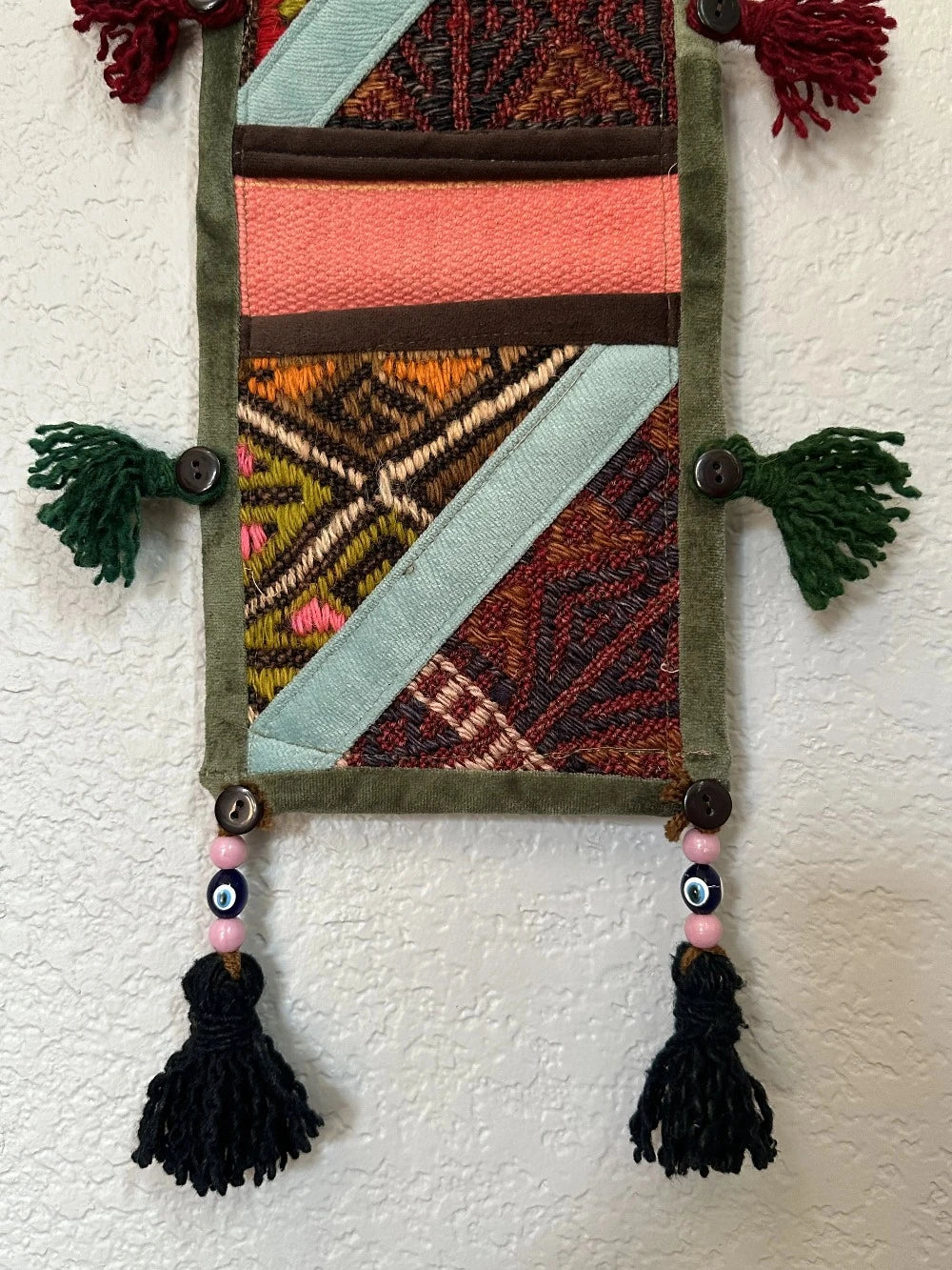 multi-colored three pocket wall organizer made from scraps of colorful Turkish kilim rugs with yarn tassels at each end