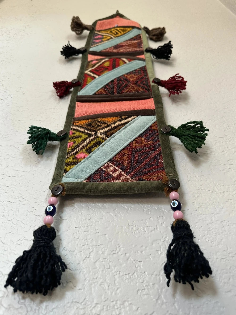 multi-colored three pocket wall organizer made from scraps of colorful Turkish kilim rugs with yarn tassels at each end