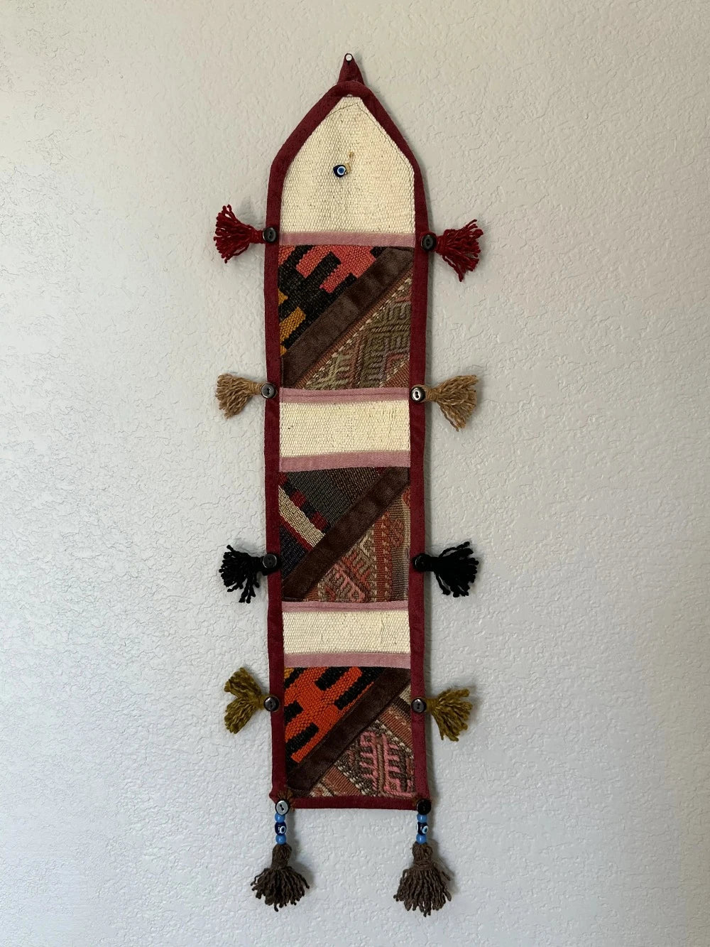 multi-colored three pocket wall organizer made from scraps of colorful Turkish kilim rugs with yarn tassels at each end