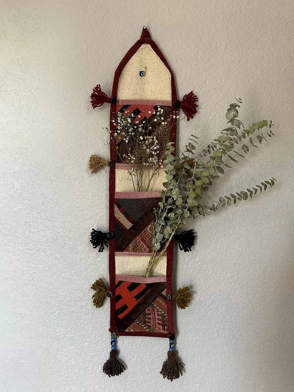 multi-colored three pocket wall organizer made from scraps of colorful Turkish kilim rugs with yarn tassels at each end