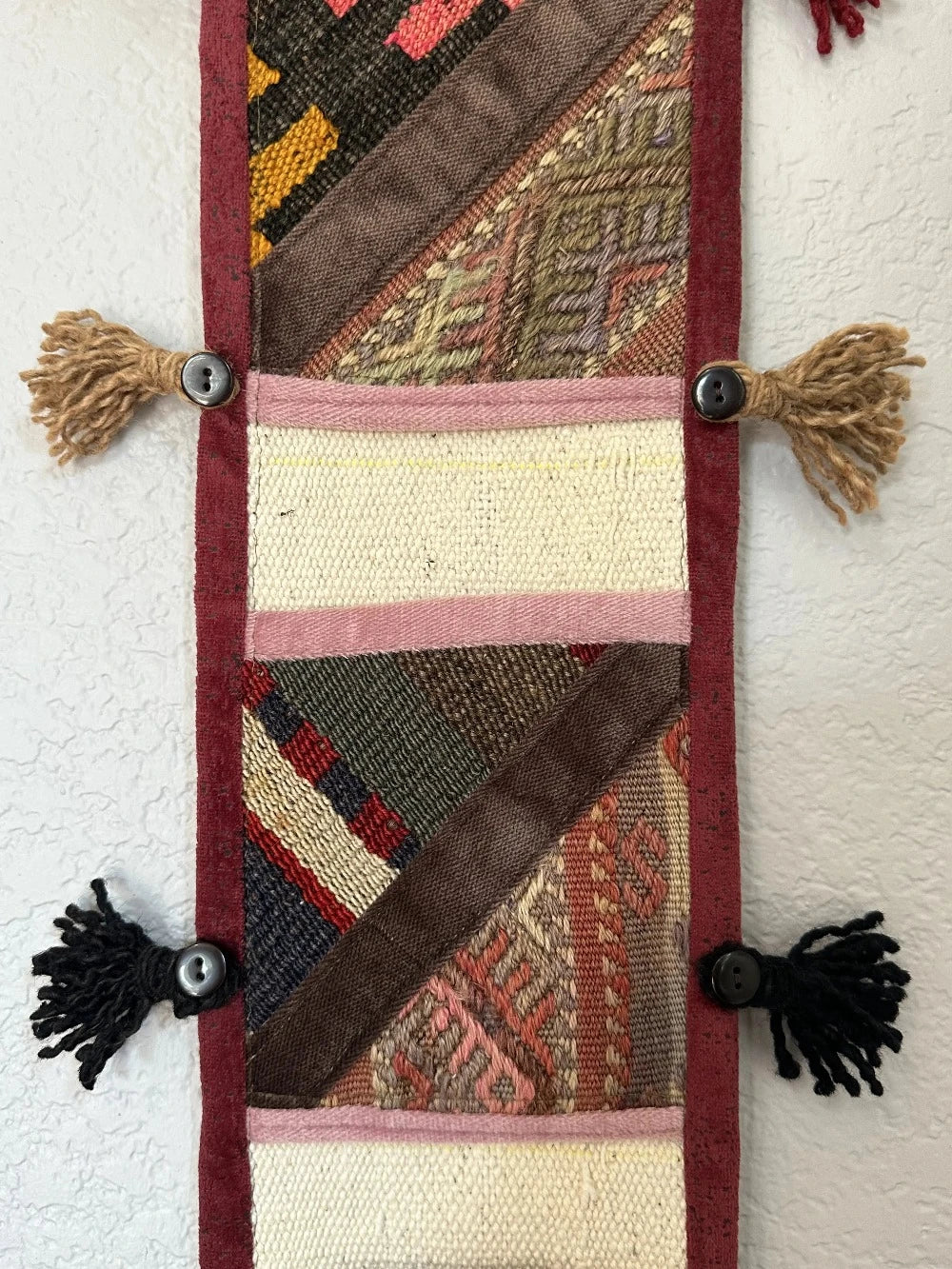 multi-colored three pocket wall organizer made from scraps of colorful Turkish kilim rugs with yarn tassels at each end