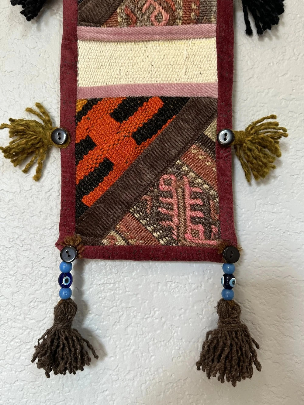 multi-colored three pocket wall organizer made from scraps of colorful Turkish kilim rugs with yarn tassels at each end