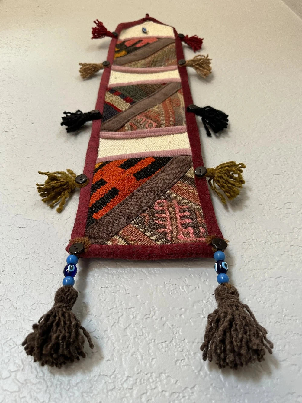 multi-colored three pocket wall organizer made from scraps of colorful Turkish kilim rugs with yarn tassels at each end