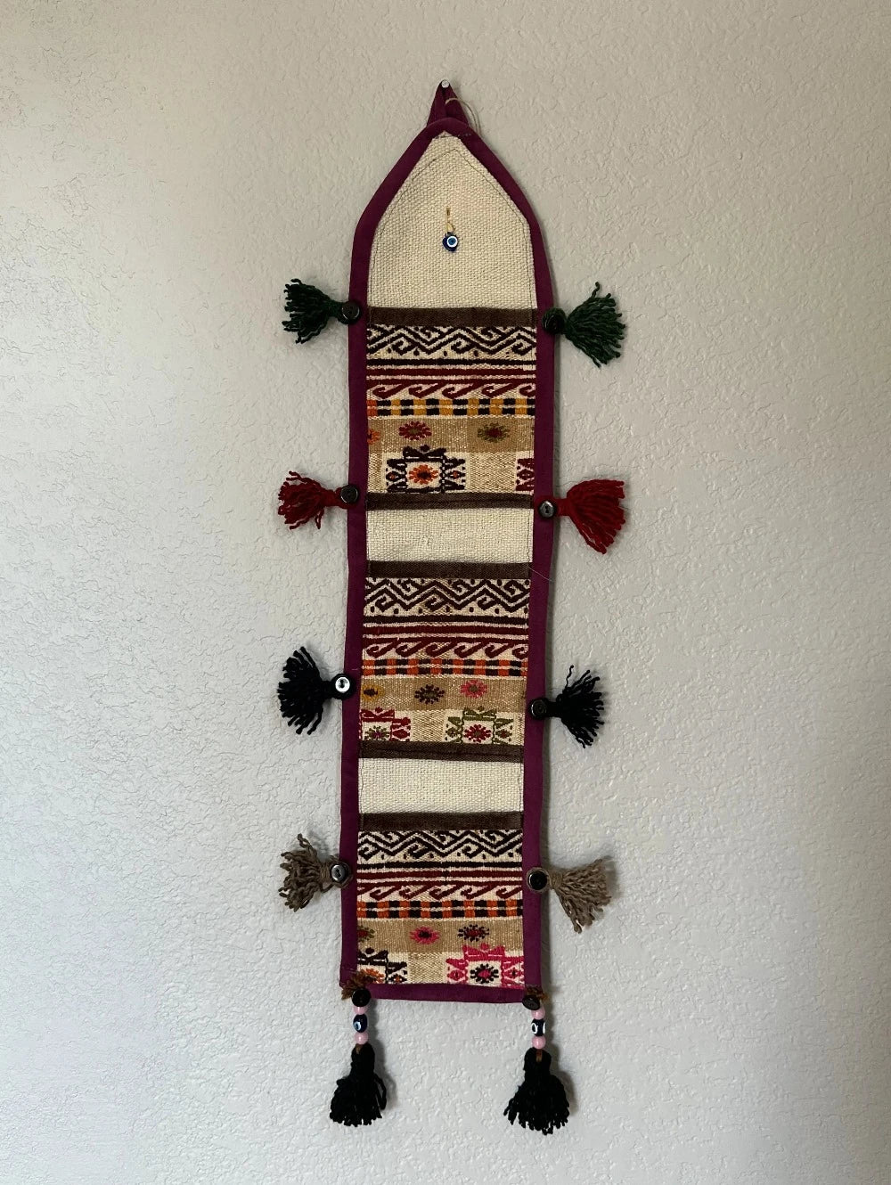 multi-colored three pocket wall organizer made from scraps of colorful Turkish kilim rugs with yarn tassels at each end