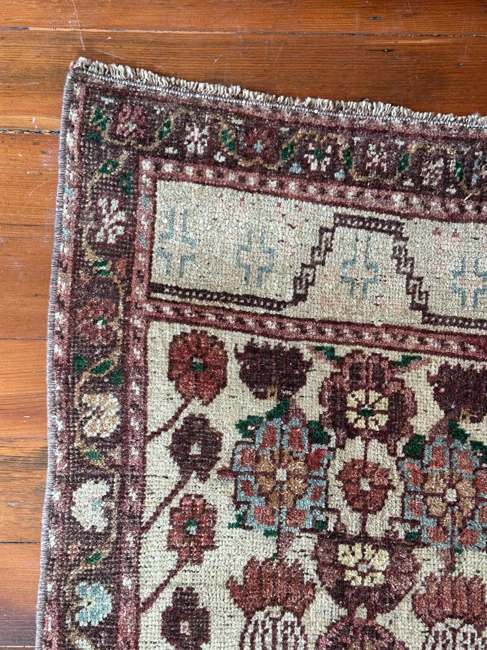 Vintage Turkish wool rug with a floral tree of life design in burgundy, green, and ivory tones, featuring a detailed border of small floral motifs.